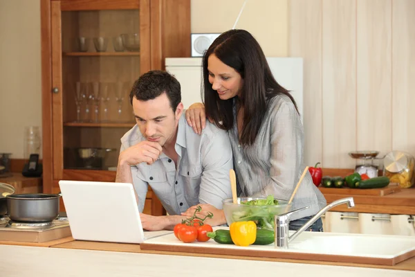 Pareja mirando un portátil en su cocina — Foto de Stock