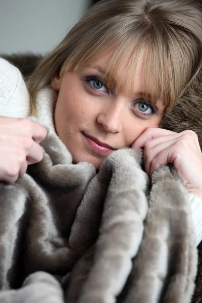 Woman snuggling under a furry blanket — Stock Photo, Image