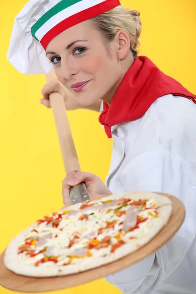 Woman putting pizza in oven — Stock Photo, Image