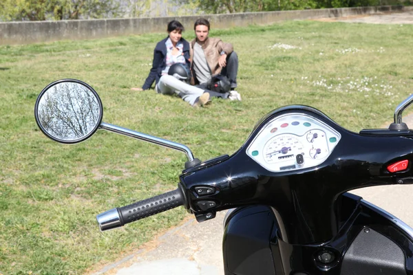 Motocicleta estacionada en la hierba y la pareja —  Fotos de Stock