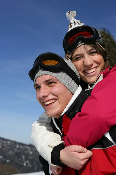 Mannen ger sin flickvän en piggy-back i snön — Stockfoto