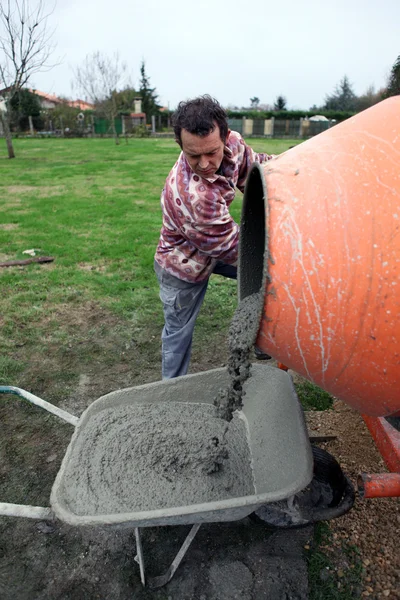 Człowiek wylewanie cementu do taczki — Zdjęcie stockowe