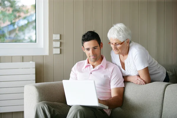 Jovem e uma mulher idosa olhando para um laptop — Fotografia de Stock