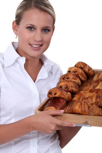 Female baker bringing croissants on a plate — Stock Photo, Image