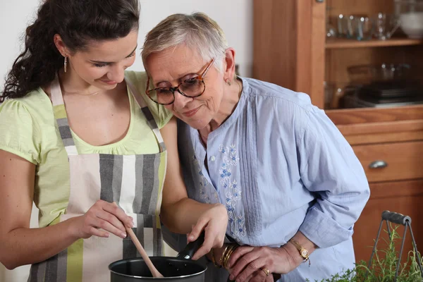 Young preparing meal to senior Stock Image