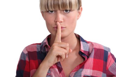 Young woman with a blunt fringe holding her finger to her lips clipart