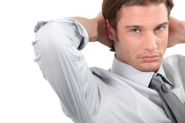 Young businessman sitting with arms behind head. clipart