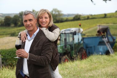 Couple with wine glass in front of vineyard clipart