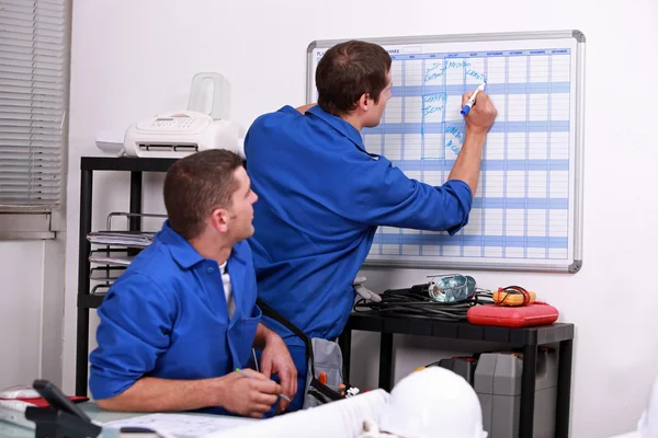 Trabalhadores manuais escrevendo em um calendário — Fotografia de Stock