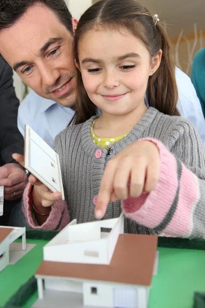 Klein meisje spelen met schaalmodel van huisvesting — Stockfoto