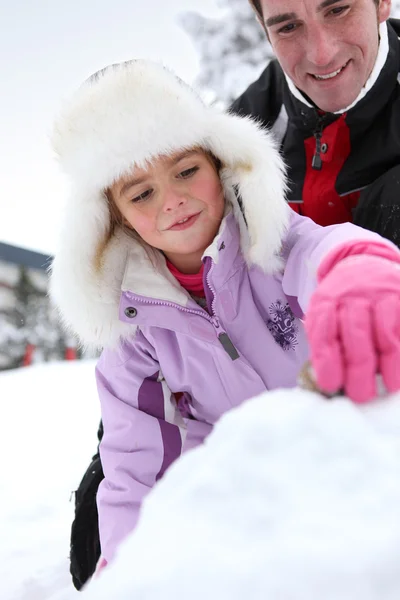 Far och dotter leker i snön — Stockfoto