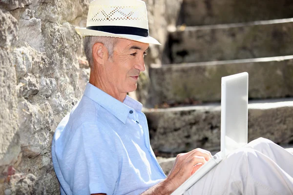 Elderly man sat on steps with laptop — Stock Photo, Image