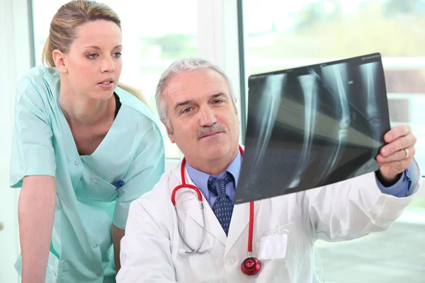 Médico e assistente examinando raio-X — Fotografia de Stock