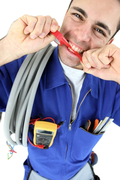 Eletricista mordendo pedaço de plástico — Fotografia de Stock