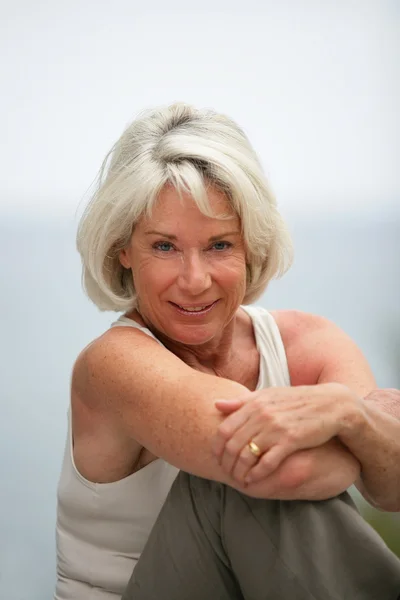 Happy gray-haired lady sat by the coast — Stock Photo, Image