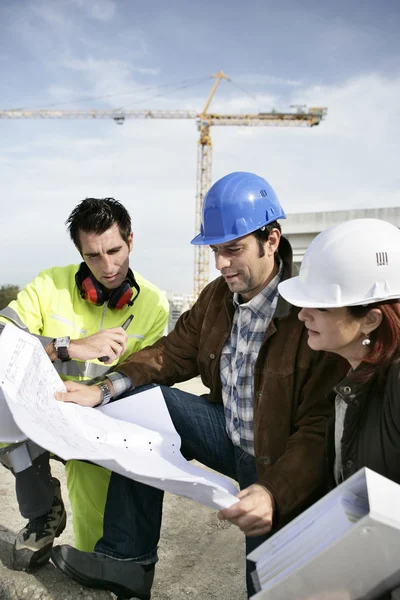 Bouwteam kijken naar plannen — Stockfoto