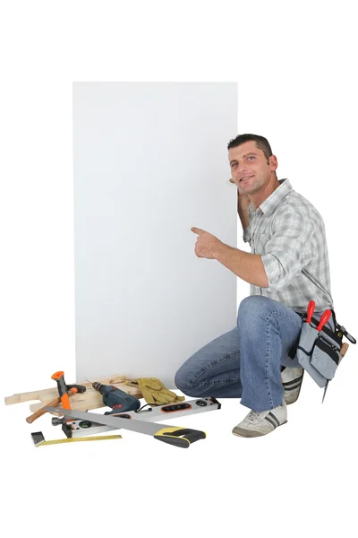 Handyman apontando para um sinal em branco — Fotografia de Stock
