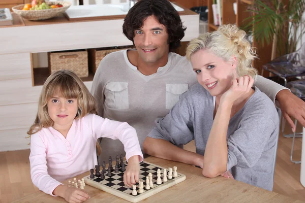 Девочка играет в шахматы со своими родителями — стоковое фото
