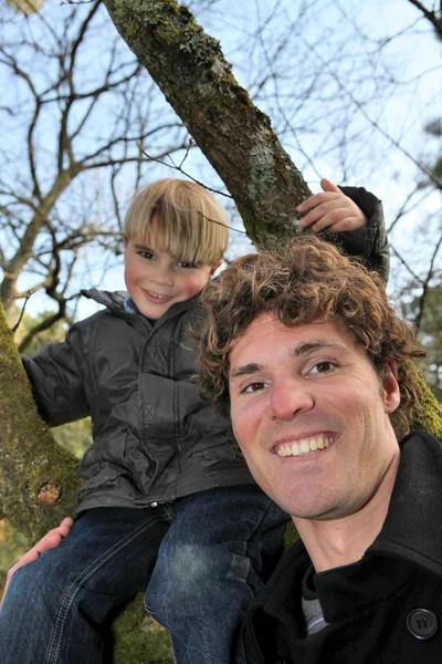 Menino escalando árvore com o pai — Fotografia de Stock
