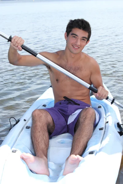 Genç adam bir kano kürek çekmeye — Stok fotoğraf