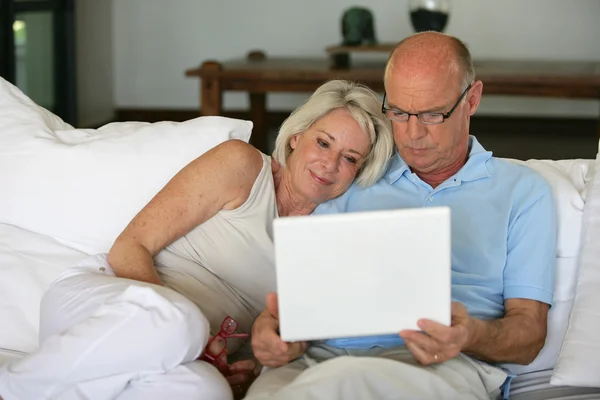 中年夫妇坐在沙发上用的笔记本电脑 — 图库照片