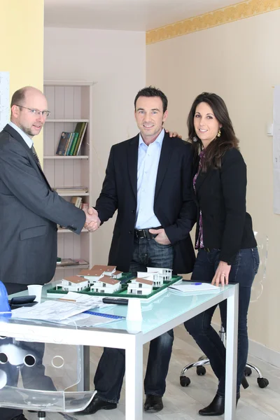 Architect stood with young couple concluding deal — Stock Photo, Image