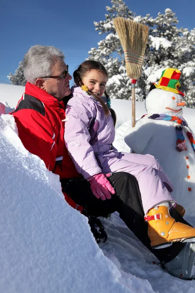 Little girl making a snowman with grandpa — Zdjęcie stockowe