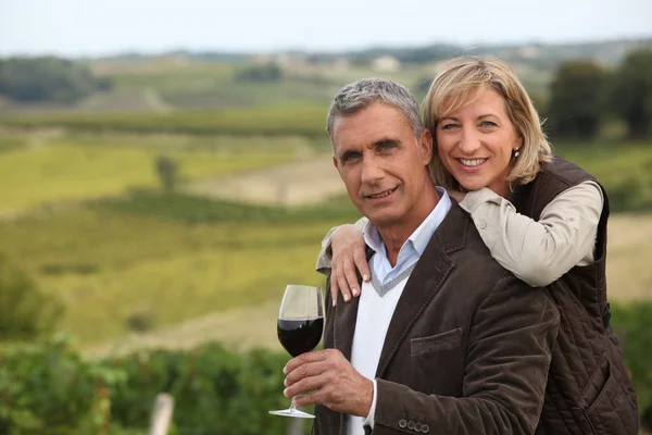 Пара с бокалом вина перед виноградником — стоковое фото