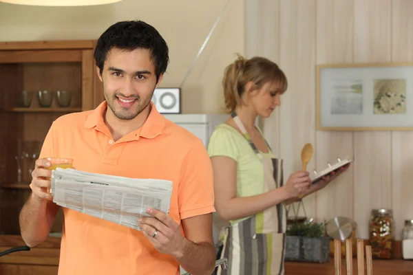 Homem lendo um jornal em sua cozinha — Fotografia de Stock