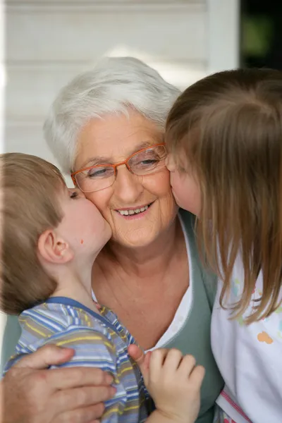Nietos besando a la abuela — Foto de Stock