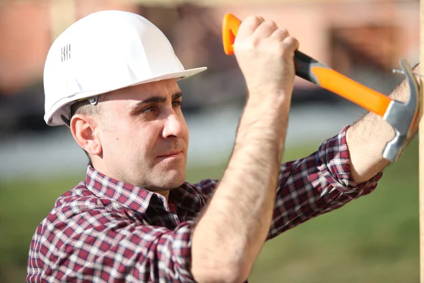 Constructor sacando clavos con un martillo — Foto de Stock