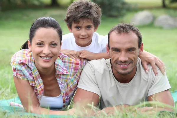 Föräldrar och son liggande i gräset — Stockfoto