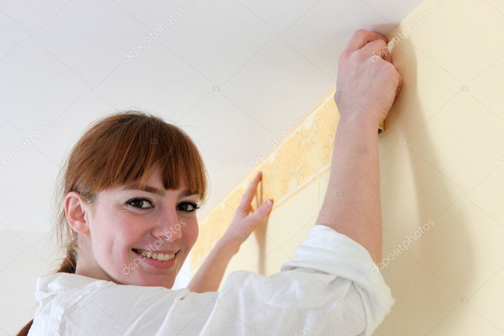 Female decorator hanging wallpaper border — Stock Photo © photography33
