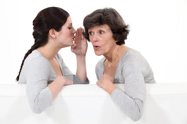 Vrouw aan haar moeder fluisteren — Stockfoto