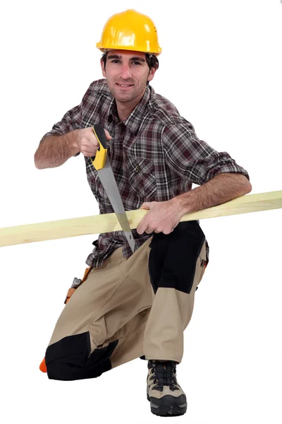 Um carpinteiro serrar uma tábua de madeira . — Fotografia de Stock
