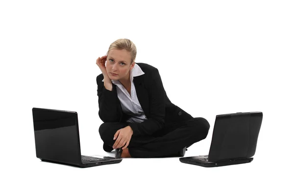 Businesswoman sat on the floor with two laptops — Stockfoto