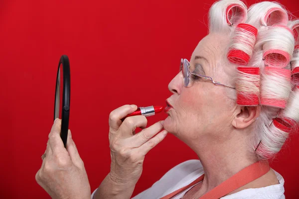 Vrouw met krulspelden zetten lippenstift — Stockfoto