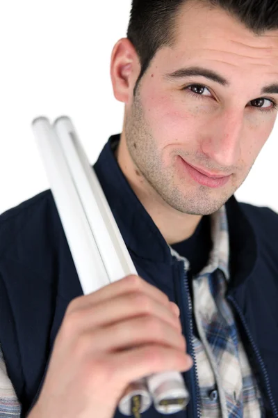 Young man with a couple of linear fluorescent lightbulbs — Stock Photo, Image