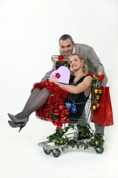 Casal com carrinho cheio de presentes de Natal — Fotografia de Stock