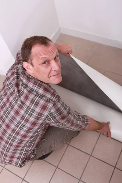 Muž rozvinutí koberec — Stock fotografie