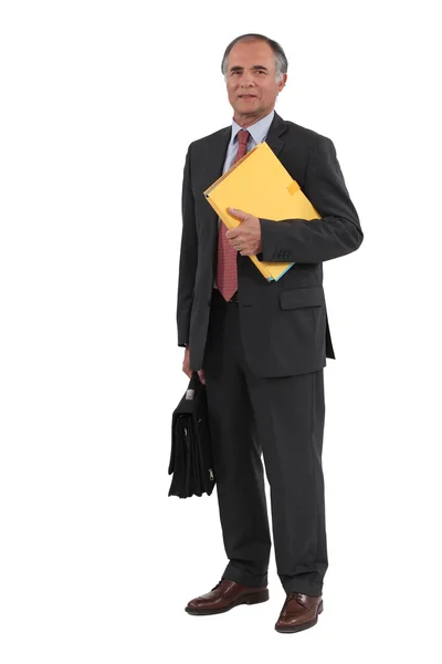 Uomo d'affari maturo che tiene cartelle e una valigetta — Foto Stock