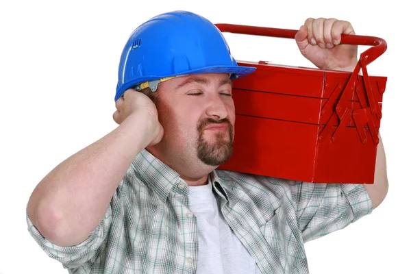Byggnadsarbetare som lyssnar till söta ljudet av hans verktygslåda Stockfoto