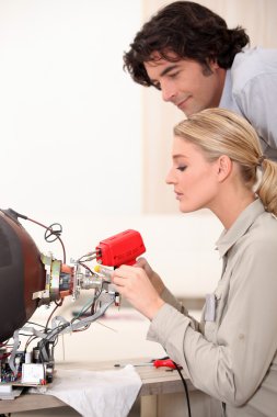 Woman repairing a television set clipart