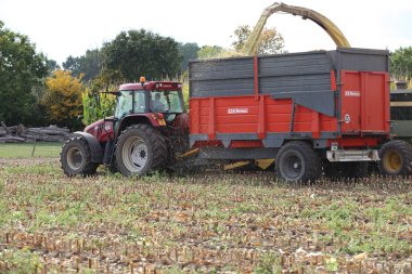 Tractor pulling trailer through field clipart