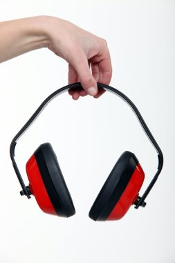 Hand holding a pair of ear defenders clipart