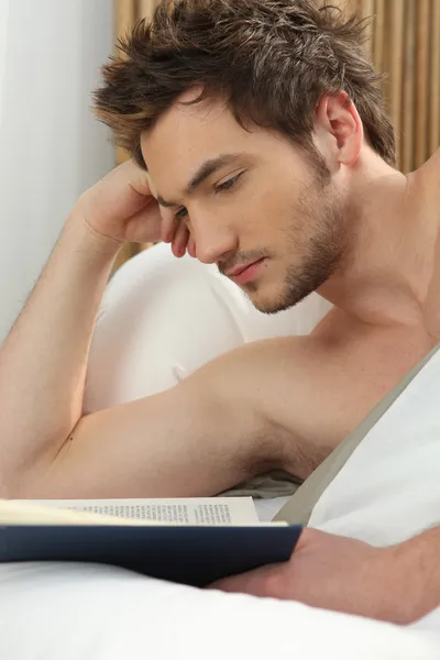 Homem lendo na cama — Fotografia de Stock