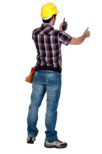 Arbetstagaren tittar på sin walkie talkie och göra tummen upp skylt — Stockfoto