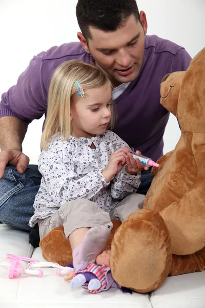 Man with little girl playing with teddy bear — Stock Photo, Image