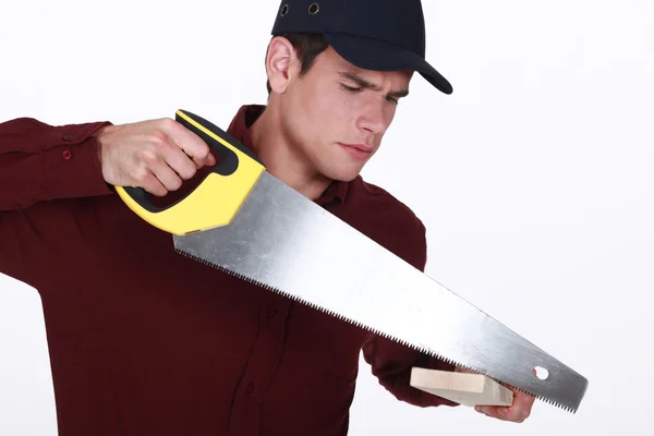 Uomo che usa una sega per tagliare una tavola di legno — Foto Stock