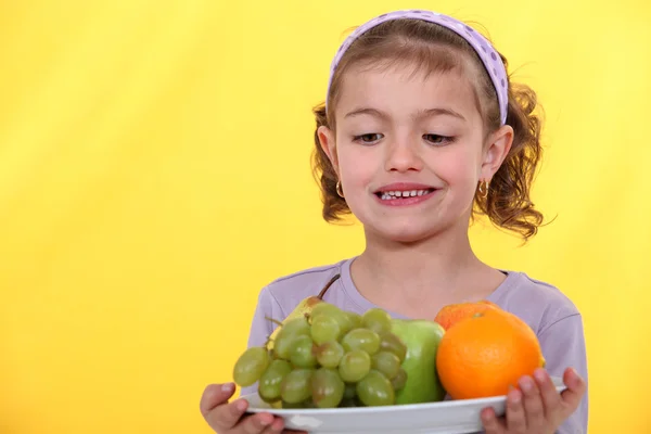 Kleines Mädchen mit einem Teller voller Früchte — Stockfoto